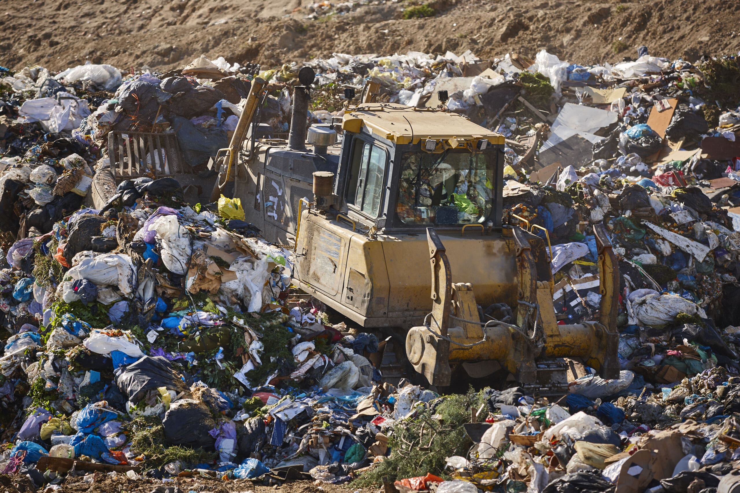 Heavy machinery shredding garbage in an open air landfill. Pollu